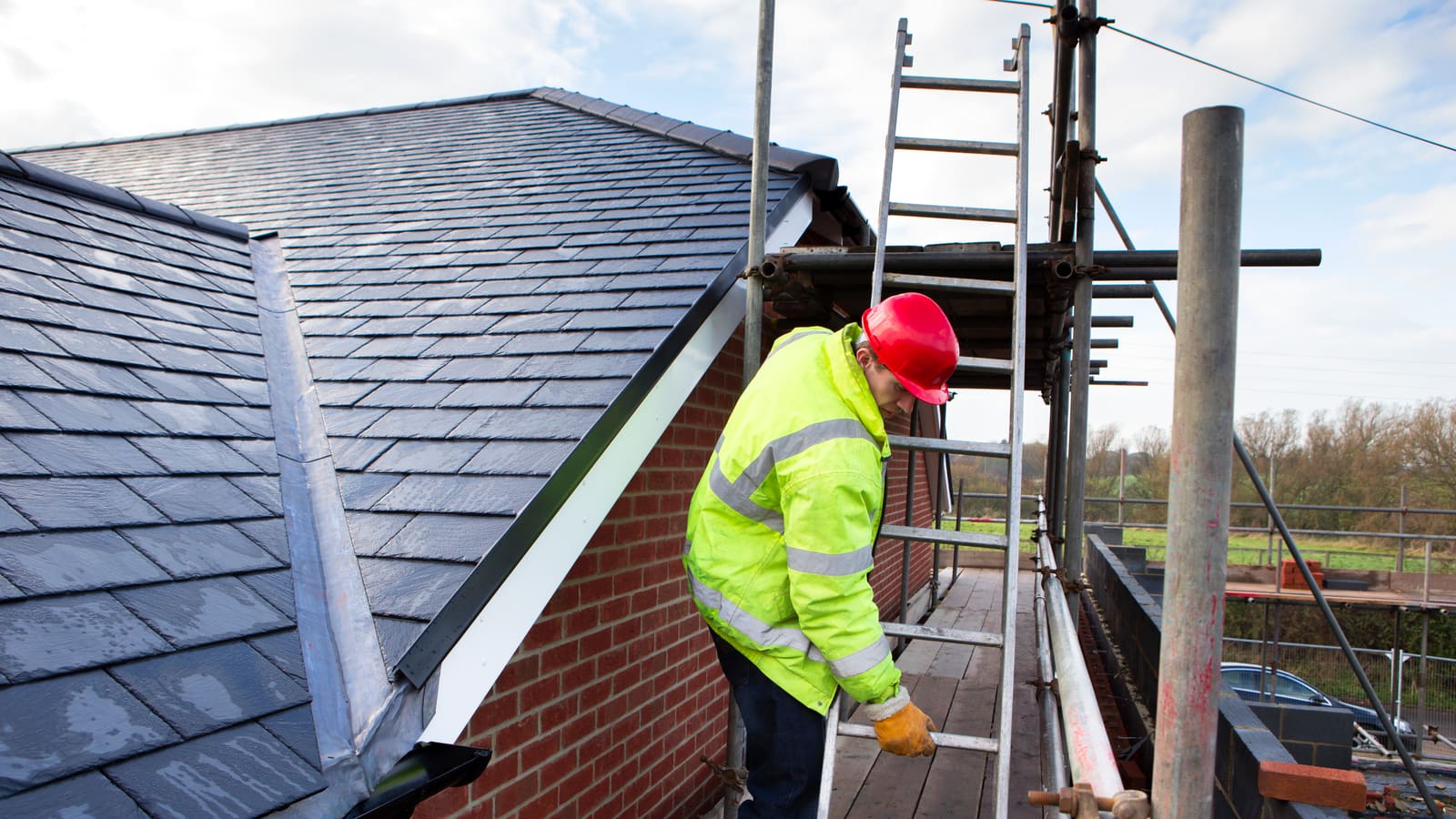 Roofer fitting a new slate roof on scaffolding